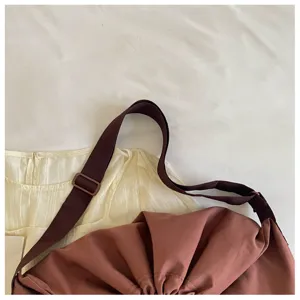 Détail de sangle de sac bandoulière marron, boucle réglable et design froncé vue de près.