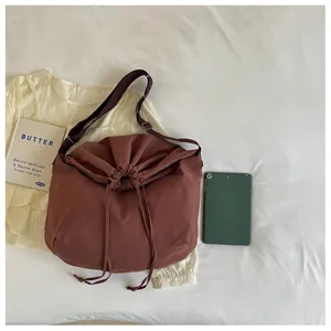 Vue détaillée du sac bandoulière marron à cordon montrant le tissu souple et la sangle.