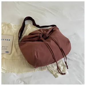 Vue détaillée du grand sac bandoulière marron à cordon, sac souple décontracté hobo porté épaule.