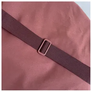 Gros plan sur la sangle réglable et la boucle d'un sac bandoulière violet, tissu solide.