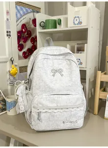 Grijs esthetisch schoolrugzakdetail met strikborduursel, kantafwerking en voorvak.