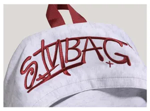 Detail view of a heather grey backpack with red embroidered lettering and durable top hoop.