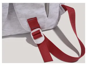 Close-up of backpack strap buckle and red webbing detail, durable fabric design.