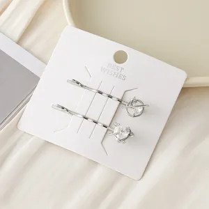 Gros plan de pinces à cheveux en métal avec des motifs de planète et de cœur en zircon sur carte.