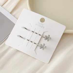Gros plan détaillé de pinces à cheveux argentées avec fleurs en zircon sur carte blanche.