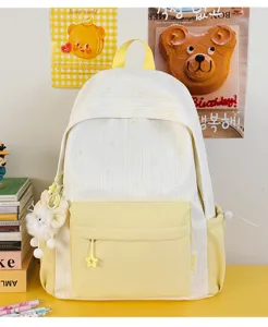 Gedetailleerd overzicht van de esthetische wit-gele gestreepte canvas rugzak met leuke pluche hanger.