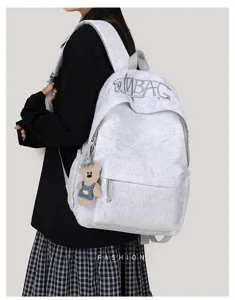 Detailed view of large capacity canvas school backpack with cute bear pendant for daily commute.