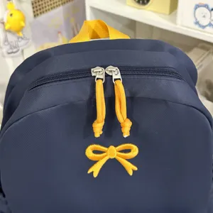 Donkerblauwe schoolrugzak met gele strik borduursel en dubbele ritssluiting voor studenten.