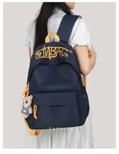 Detail view of casual canvas backpack with embroidered letter design and cute bear pendant.