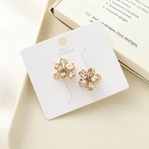 Exquisite crystal flower stud earrings detail on white display card, sparkling gold jewelry.