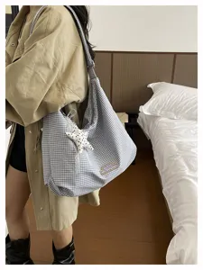 Detail van geruite schoudertas, stoffen hobo tas met sterhanger en kanten afwerking.