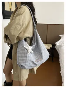Gedetailleerd shot van ruitjes hobo schoudertas met sterhanger en borduurwerk voor dagelijks gebruik.