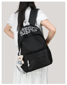 Detailed view of the black canvas embroidered letter backpack with cute bear pendant for daily use.