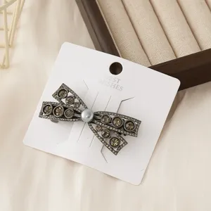 Detail shot of the elegant rhinestone bow hair clip displayed on a white card, close-up.