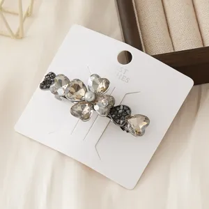 Detailed view of a sparkling crystal heart hair clip on white card, elegant design.