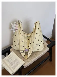 Detailopname van de gele polka dot hobo cloud tas met bedels op een geweven kruk.