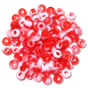 Gros plan détaillé de perles barils en acrylique rouge et blanc, idéal pour bijoux et chaînes.