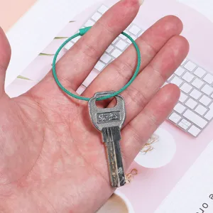 Close-up detail of green steel wire key ring rope with metal key accessory, durable design.