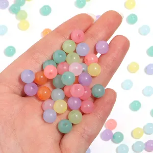 Close-up detail of colorful acrylic jelly round beads held in hand for DIY jewelry making.