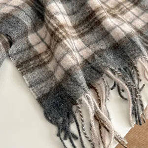 Close-up view of cozy wool blend plaid scarf detail with soft fringe and warm winter texture.