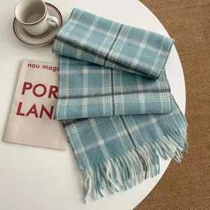 Blue plaid wool scarf detail folded nicely on white table with cup and magazine decor.