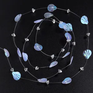Vue détaillée de perles de coquillage irisées sur fil de pêche, idéal pour loisirs créatifs.