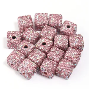 Gros plan de perles cube en argile strass rose, details d'accessoires cristal brillants.