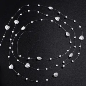 Vue détaillée de perles blanches et cœurs sur fil de pêche transparent pour vos loisirs.