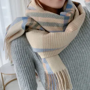 Detail shot of a cozy women's plaid winter scarf, soft cashmere-feel fabric with chic fringe.