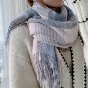 Closeup of soft plaid winter scarf with fringe, cozy pink blue grey herringbone knit texture.