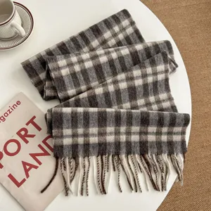 Detailed view of a cozy brown and white plaid winter scarf with fringed edges, flat lay.