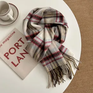 Close-up detail of cozy plaid winter scarf with fringe, lifestyle flat lay on white table.