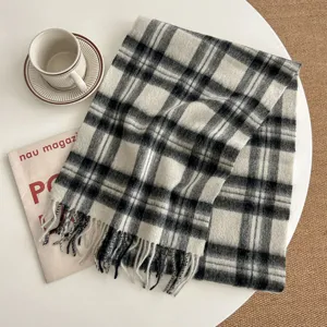 Black and white plaid scarf detail shot, cozy woolen texture with elegant fringe trim.