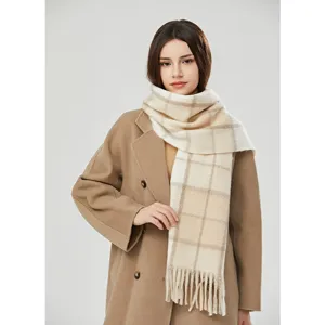 Close-up detail of a cozy beige plaid tassel scarf worn by model in winter coat.