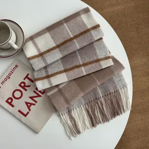 Detailed view of the cozy British plaid wool scarf with soft fringe in elegant brown.