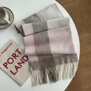 Detailed view of winter plaid scarf with soft pink, brown and beige color blocks and fringe.