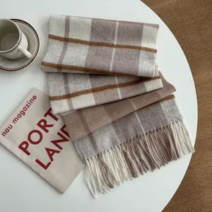 Cozy plaid woolen scarf detail with fringe, warm winter accessory in beige and brown tones.