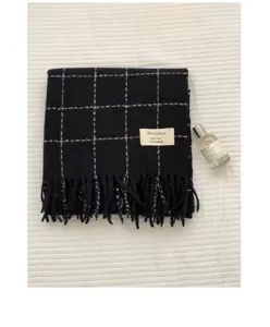 Detail shot of the black and white grid patterned winter cashmere feel scarf with cute tassel ends.