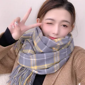 Detail shot of cozy grey plaid scarf with yellow stripes and soft fringe. Perfect winter wear.