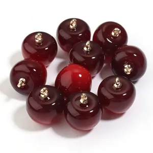 Primer plano de dijes acrílicos rojos brillantes con argollas doradas para manualidades.