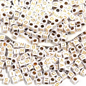 Close up detail of white acrylic square beads with gold letter print for DIY jewelry making.