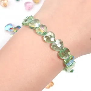 Detailed closeup of green crystal heart faceted bead bracelet worn on wrist showcasing sparkle.