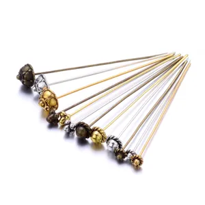 Close-up detail of assorted metal headpins and flower pins in gold, silver and bronze.