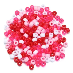 Gros plan détail de perles tonneau en acrylique rouge rose et blanc pour bijoux artisanaux DIY.