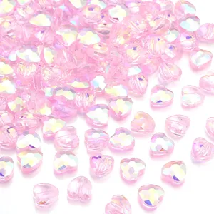 Detailed shot of sparkling pink crystal heart beads with faceted iridescent finish for DIY jewelry crafting.