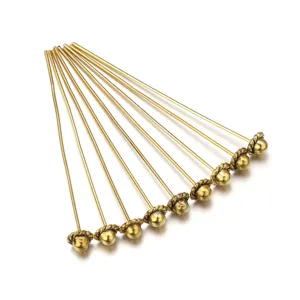 Close-up detail of golden metal ball head pins for jewelry making, DIY craft accessories view.