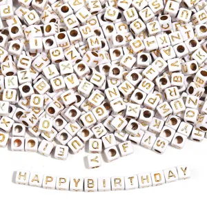Close-up detail of white acrylic square beads with gold letters spelling happy birthday, ideal for DIY.