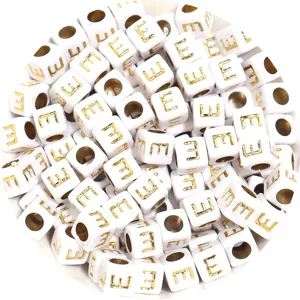 Close-up detail of white square acrylic letter beads with gold print, ideal for DIY bracelets.