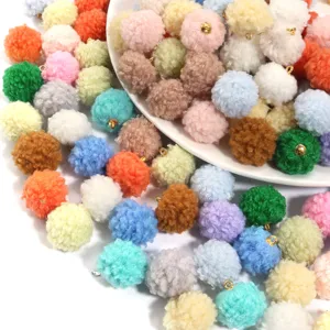 Close-up detail of 20mm fluffy plush pom pom charms with gold loops for DIY jewelry.