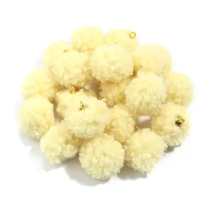 Close-up detail of fluffy teddy fleece pompom charms with gold loops, perfect for DIY jewelry.